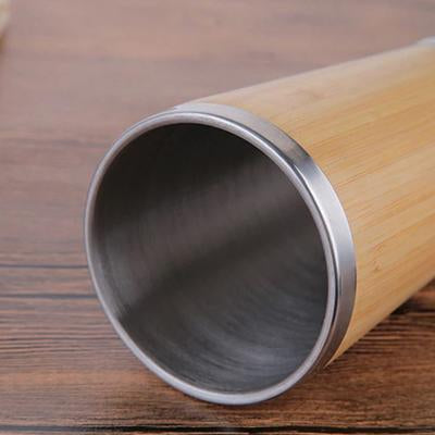 Uncovered bamboo coffee mug laid on its side showing stainless-steel interior and rim