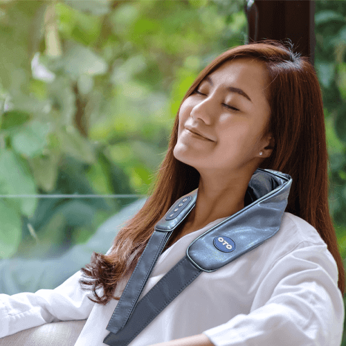 Woman relaxing with OTO Q Hug neck massager, enjoying deep tissue massage and heat therapy for ultimate comfort.