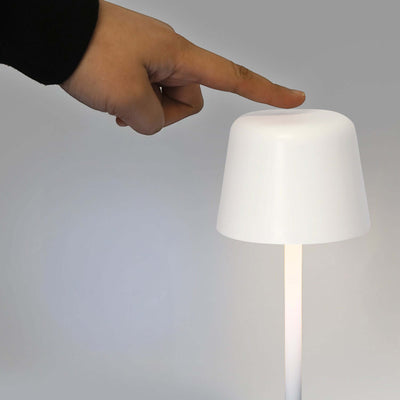 Person using touch controls on the Ember Rechargeable Table Lamp to adjust lighting settings.