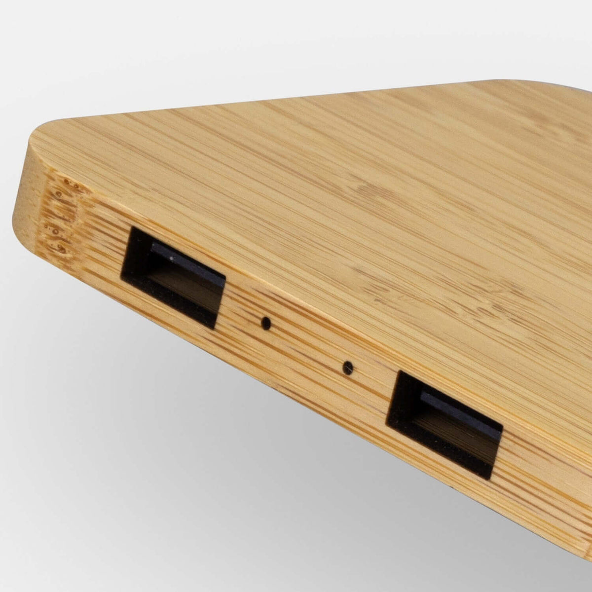 Close-up of NATURA bamboo charging hub edge showing twin USB-A ports and two small indicator openings