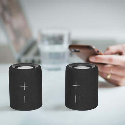 Prixton Aloha Lite Bluetooth Speaker in a stylish black design on a table with a smartphone.