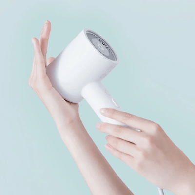 Xiaomi Mi Ionic Hair Dryer H300 being held by a hand, showcasing its compact and lightweight design.