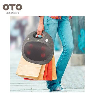 Woman carrying the OTO Handy Spa Oval back massager while holding shopping bags, perfect for on-the-go relaxation.