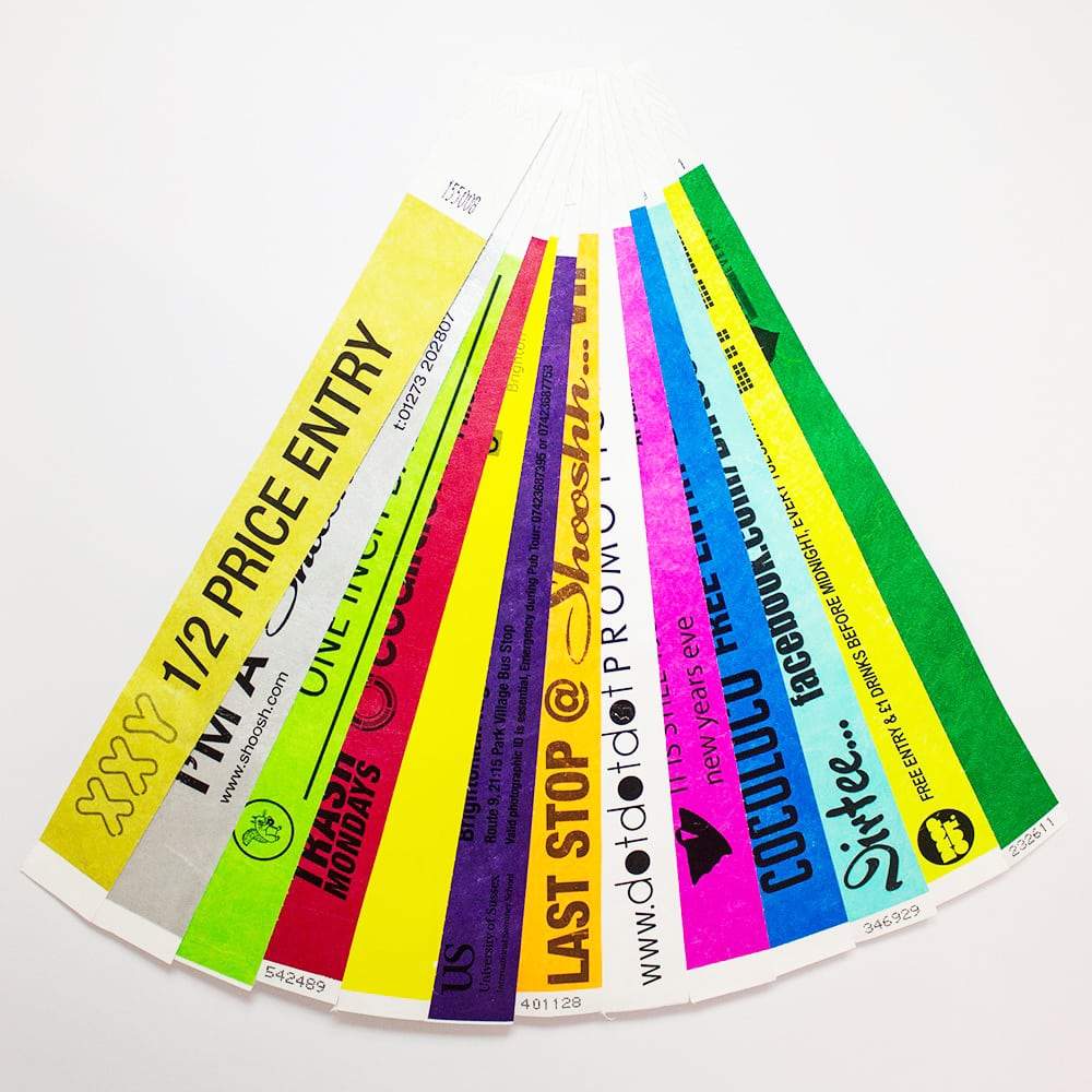 Fan of coloured Tyvek event wristbands showing sample text, logos and numbering